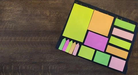 Multi-colored bright stickers of different sizes on a wooden background. Stock Photos