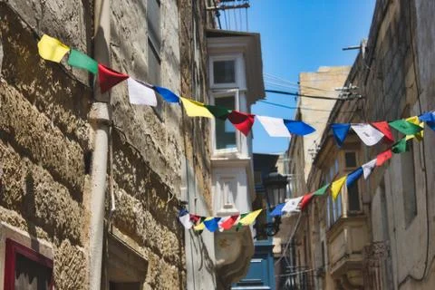 Multi-colored bunting hanging between the houses in a narrow street Foto stock