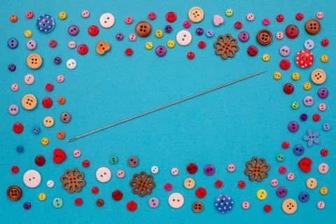 Multi-colored buttons are scattered on the table, a needle. Accessories for Stock Photos