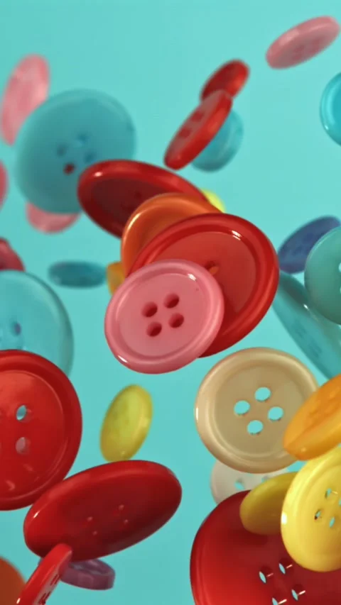 Multi-colored buttons fly on a blue background. Filmed on a high-speed camera at Stock Footage 335381517