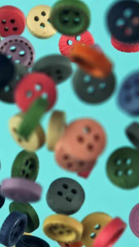 Multi-colored buttons fly on a blue background. Filmed on a high-speed camera at Stock Footage 335385200