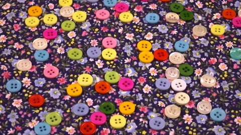 Multi-colored  buttons lie on a cotton navy fabric with a small floral pattern Stock Footage 317493322