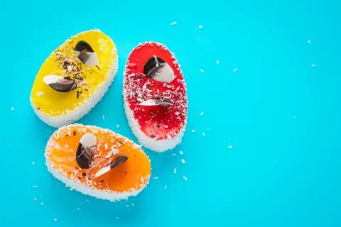 Multi colored cakes with coconut flakes on blue background. Homemade baked de Stock Photos