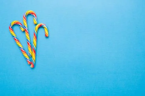 Multi-colored candy canes on a blue background, copy space Stock Photos