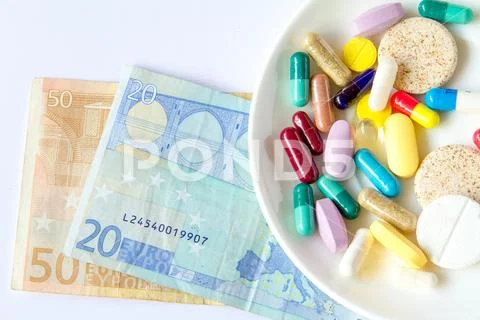 Multi-colored capsules in a saucer against the background of euro banknotes. Stock Photos