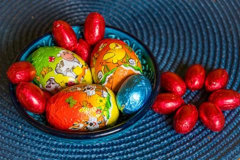 Multi-colored chocolate eggs in a blue bowl, seasoned for the feast of Easter Stock Photos