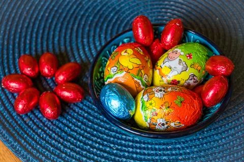 Multi-colored chocolate eggs in a blue bowl, seasoned for the feast of Easter Stock Photos