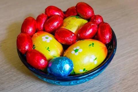 Multi-colored chocolate eggs in a blue bowl, seasoned for the feast of Easter Stock Photos