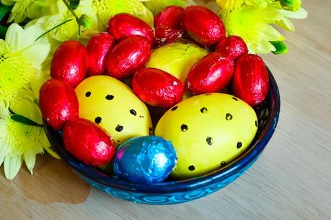 Multi-colored chocolate eggs in a blue bowl, seasoned for the feast of Easter Stock Photos