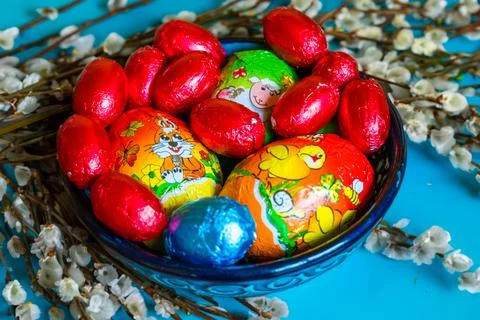 Multi-colored chocolate eggs in a blue bowl, seasoned for the feast of Easter Stock Photos