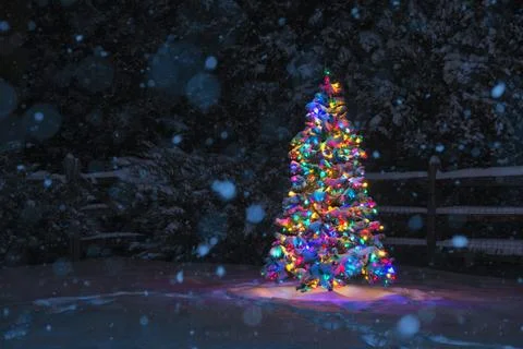 Multi-Colored Christmas tree at night while snowing Foto stock