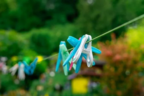 Multi-colored clothespins hang on a rope in the yard. Colorful clothespins ha Stock Photos