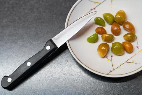 Multi-colored cloves of peeled pickled garlic for seasoning on a porcelain Stock Photos