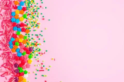 Multi-colored confectionery topping on a plain pink background with copy spac Stock Photos