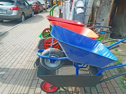 Multi-colored construction wheelbarrows are on the sidewalk Stock Photos