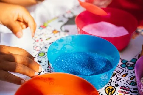 Multi-colored containers with multi-colored sand and small pebbles for children Stock Photos