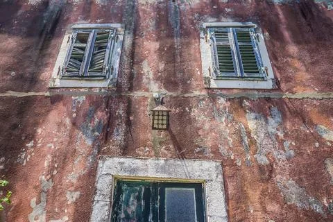 Multi-colored cracked textured plaster on an old wall with windows. 写真素材