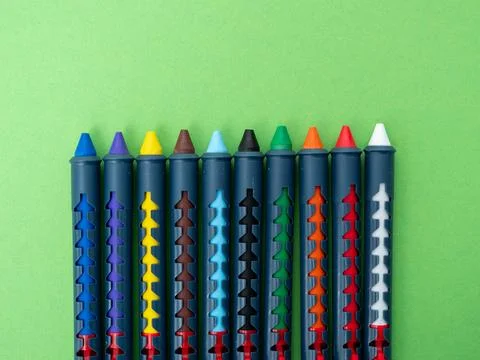 Multi-colored crayons for drawing on a green background. Stock Photos