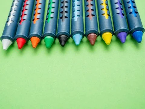 Multi-colored crayons for drawing on a green background. Stock Photos