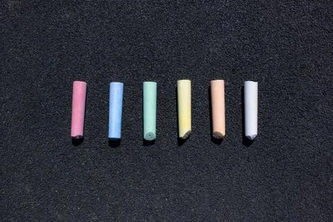 Multi-colored crayons parallel to each other on sidewalk asphalt Stockfoto's