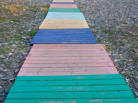 Multi-colored decking on a pebble beach. The path to the shore from different Stock Photos