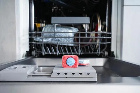 Multi-colored dishwasher tablet in a plastic dishwashing container. Close-up. Stock Photos