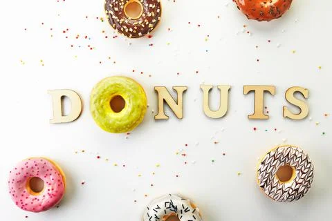 Multi Colored donuts with icing, sprinkles and the inscription donuts on white Stock Photos