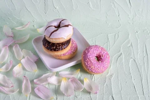 Multi-colored donuts on white dishes on a table Stock Photos