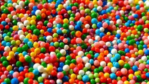 A multi-colored dragee spins on a plate. Multicolored balls. Stock Footage 87687014