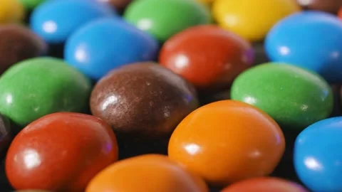 Multi-colored dragees rotate 360 degrees on a plate Stock Footage 184474415