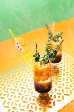 Multi-colored drinks with pieces of fruit, mint and an unusual straw. Stock Photos