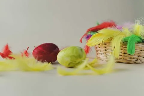 Multi-colored Easter eggs and feathers in a nest on a light background Stock Photos