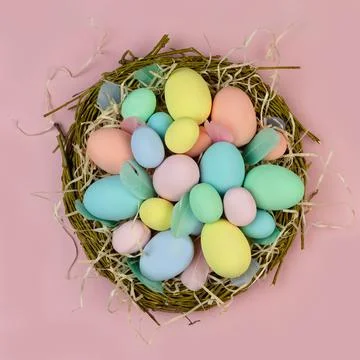 Multi-colored Easter eggs and feathers in pastel colors lie in a nest of Stock Photos