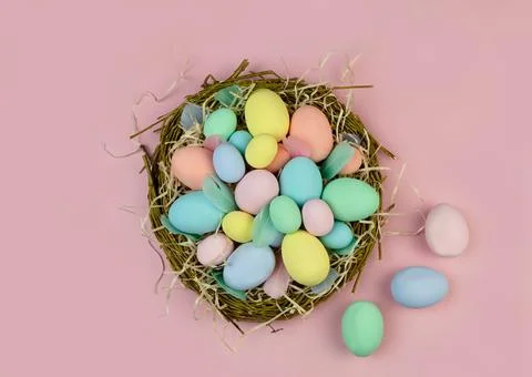 Multi-colored Easter eggs and feathers in pastel colors lie in a nest of Stock Photos