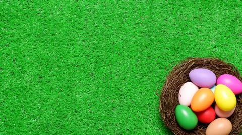 Multi colored easter eggs in birds nest on green grass lawn background Foto stock