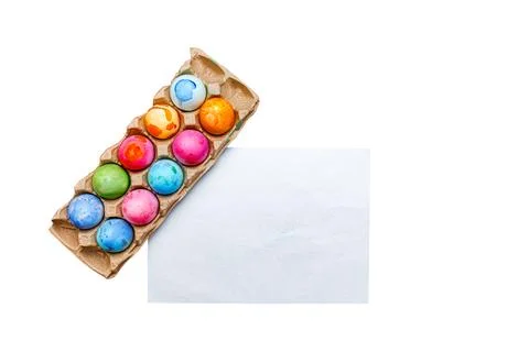 Multi-colored Easter eggs in an egg container and a white sheet on a white Stock Photos