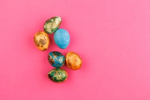 Multi-colored easter eggs lie on a pink background. Stock Photos