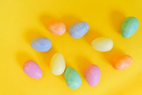 Multi-colored Easter eggs lie on a yellow background, top view Photos