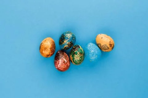 Multi-colored easter eggs lie on a blue background. Stock Photos