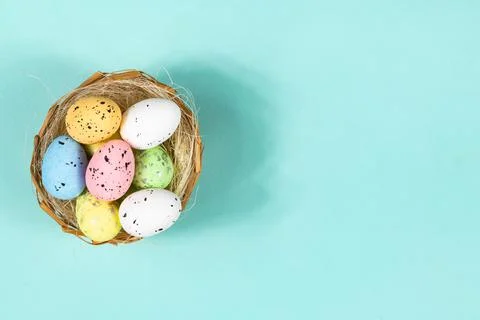 Multi-colored Easter eggs in a nest on a blue background with space for text Stock-Fotos