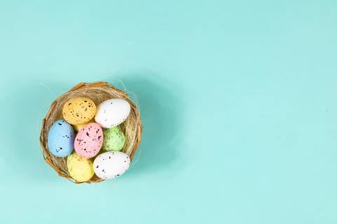 Multi-colored Easter eggs in a nest on a blue background with space for text Stock Photos