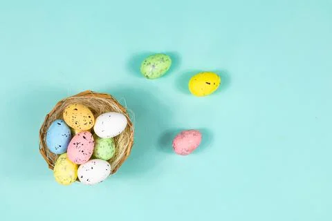 Multi-colored Easter eggs in a nest on a blue background with space for text Stock Photos