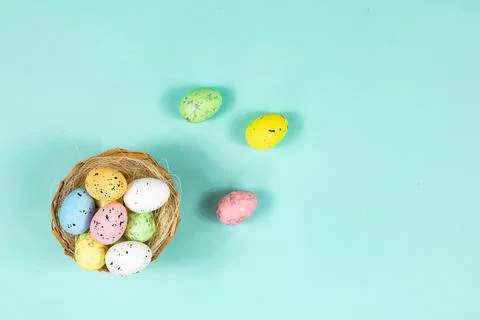 Multi-colored Easter eggs in a nest on a blue background with space for text Stock Photos