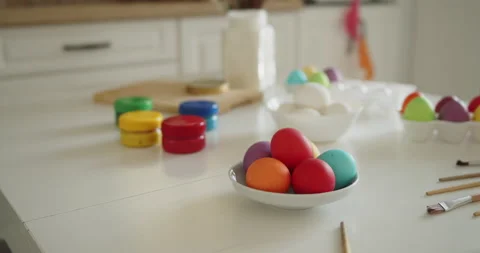 Multi-colored easter eggs, paint jars and brushes on a kitchen table Stock Footage 236794498