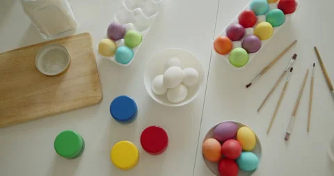 Multi-colored easter eggs, paint jars and brushes on a kitchen table top view Stock Footage 236794744