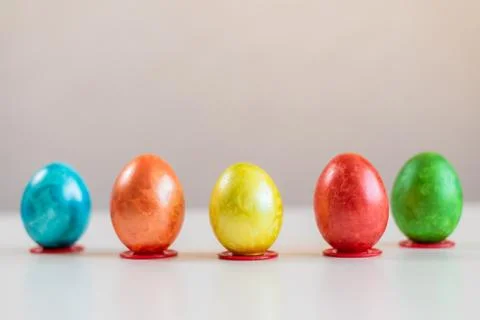 Multi-colored Easter eggs stand in a row on the table. Stock Photos