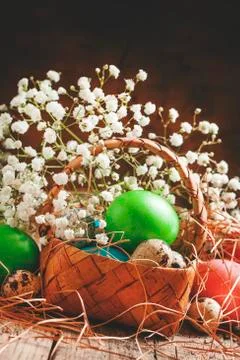 Multi-colored Easter eggs in a wicker basket in a rustic style, selective foc Stock Photos