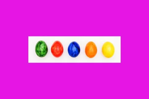 Multi-colored eggs on a purple and white background. Painted eggs. Handwork. Stock Photos