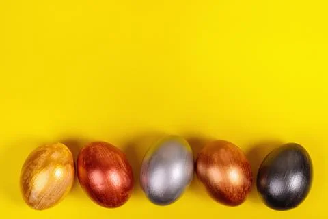 Multi-colored eggs on a uniform yellow background with place for text. Stock Photos