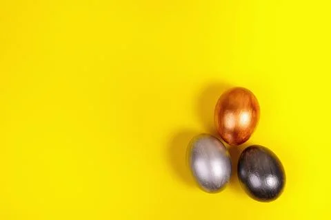 Multi-colored eggs on a uniform yellow background with place for text. Stock Photos